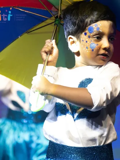 A young boy holds his umbrella, his expression full of charm and focus during the rain dance.