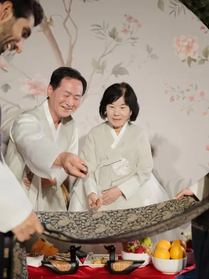 A heartwarming moment of respect as the couple serves tea to their parents during the Paebaek, a key part of the Korean wedding tradition.