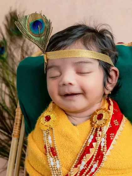 A sleeping newborn Krishna, dreaming sweet dreams. The peacock feather and traditional jewelry add a divine touch to this peaceful and serene portrait.