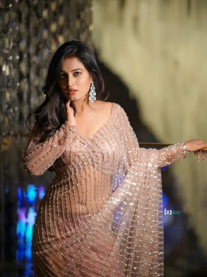 The lighting in this portrait is soft and flattering, creating a glamorous yet approachable look. The focus is on the subject's expression and the beautiful details of the saree.