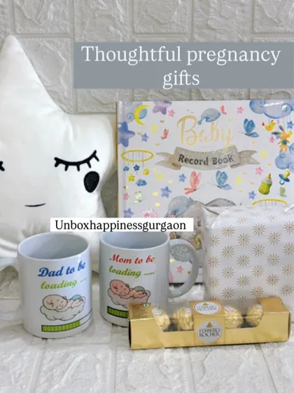 A flat lay of the thoughtful pregnancy gifts I offer, including a star cushion, parent mugs, a baby record book, and chocolates.