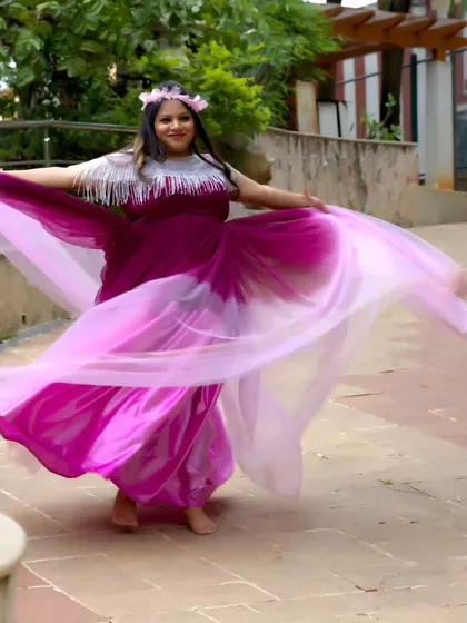 A beautiful shot of a woman twirling in a dual-toned pink and purple maternity gown, with the fabric flowing around her.