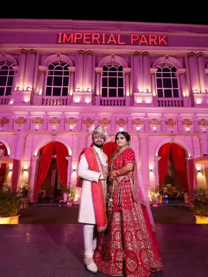 A magnificent wide shot of the couple standing before the Imperial Park venue. This photo showcases the grandeur of the location and the scale of their celebration.