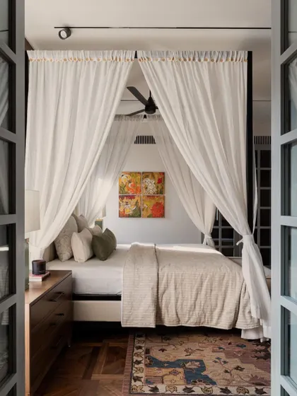 The ethereal four-poster bed in the Pràna master suite, a space designed to be a sanctuary. The view through the French doors hints at the private balcony beyond.