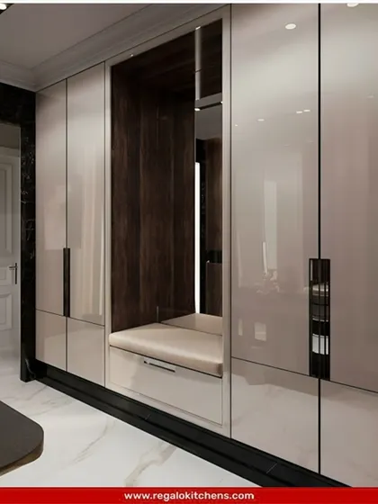 This wardrobe includes a clever built-in bench seat, creating a cozy nook for putting on shoes. The high-gloss finish and dark wood accents provide a modern, high-contrast look.