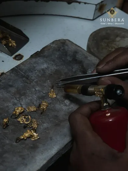 The fire of creation is in our hands. An artisan uses a blowtorch for precision soldering on small gold components, a crucial step in crafting intricate jewellery. This level of detail is what defines our manufacturing process and ensures lasting quality.