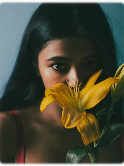 A close-up shot with a yellow flower, where only the model's intense eyes are visible.