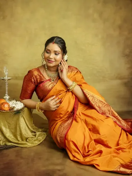 A graceful pose on the floor, surrounded by the rich fabric of your saree and traditional lamps. This shot is artistic, elegant, and full of warmth.