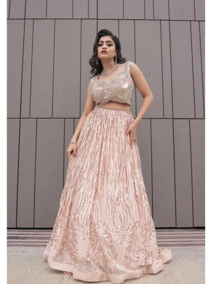 A full-length power pose in the sequin lehenga against a modern, minimalist grey wall.
