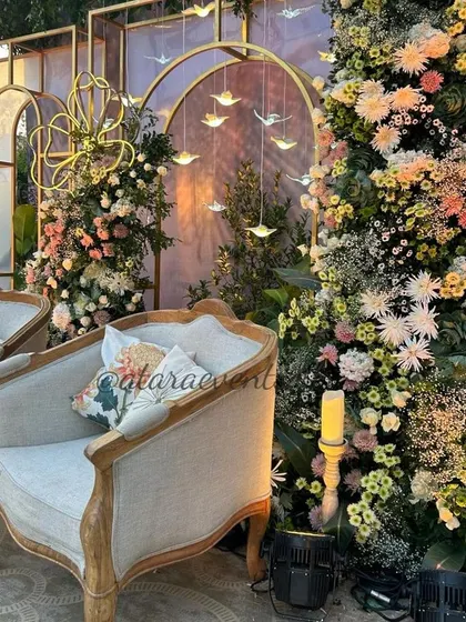 A close-up of the elegant baby shower stage. The vintage-style chairs, lush floral arrangements, and hanging bird details create a sophisticated and whimsical atmosphere.