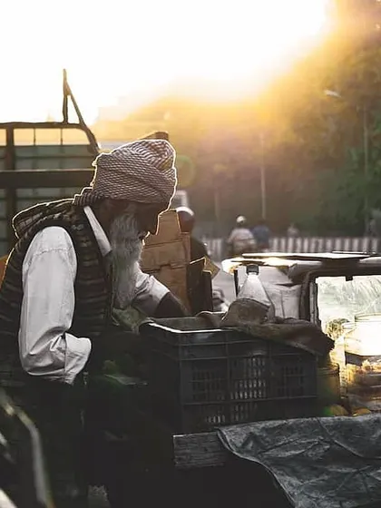 A street vendor at his cart, bathed in the golden light of the setting sun. This image captures the mood and grit of urban life.