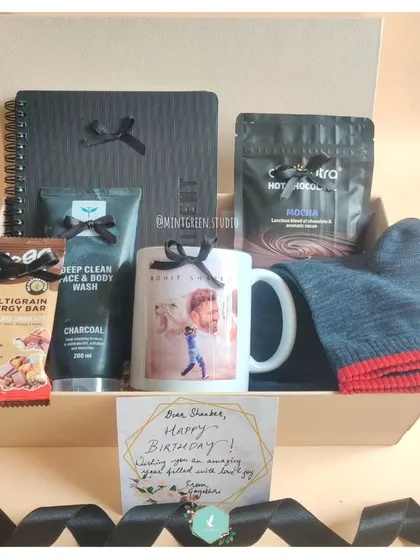 This birthday hamper was curated based on the recipient's interests. It features a personalized mug with a photo, a deep clean face wash, a multigrain energy bar, and a cozy beanie, making it a thoughtful and practical gift.
