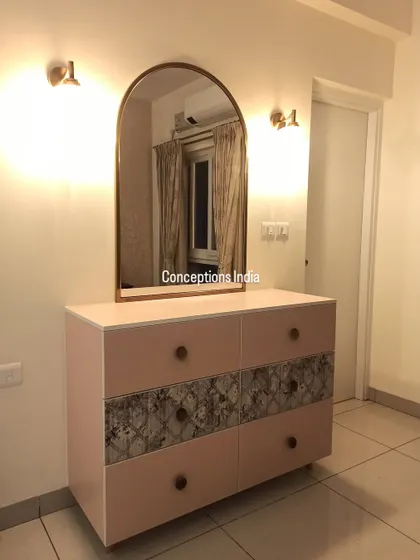 A contemporary and minimalist dresser with a chest of drawers, featuring an arched mirror and elegant wall sconces for a refined look.