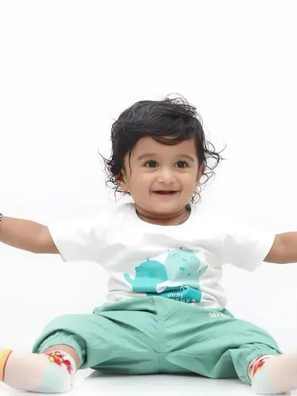 A happy baby sits and smiles while holding onto the hands of two adults, feeling safe and loved.
