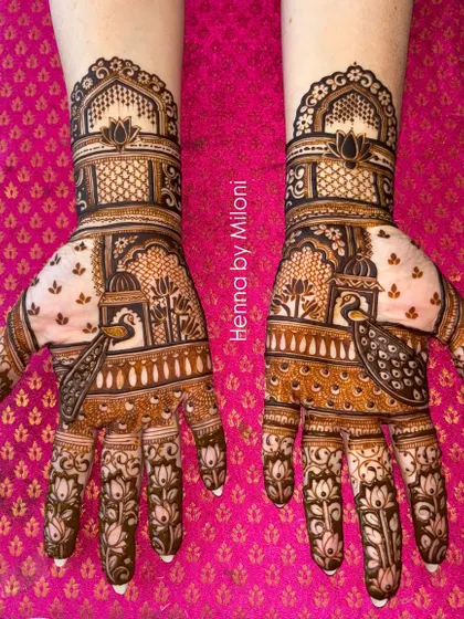 A classic Rajasthani bridal mehendi featuring intricate jharokha windows and peacock motifs. The design is symmetrical across both hands, creating a stunning, regal look for the modern bride.