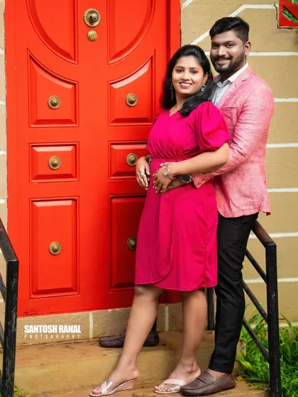 A bold and colorful portrait with the couple posing against a bright red door.