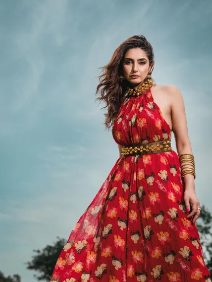 A low-angle shot against a bright blue sky, making the model in her vibrant red dress appear powerful and statuesque. This technique is great for creating heroic and memorable fashion images.