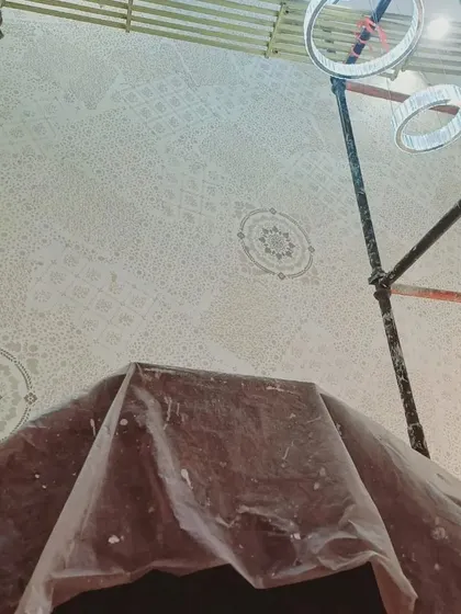 A closer look at the detailed stencil work on a ceiling. Notice how we protect the surrounding areas, like the chandelier, to ensure a clean and professional application. This level of detail is part of our standard process.