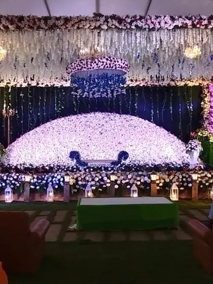 A wide shot of a magnificent reception stage, featuring a massive dome of flowers and dramatic lighting.