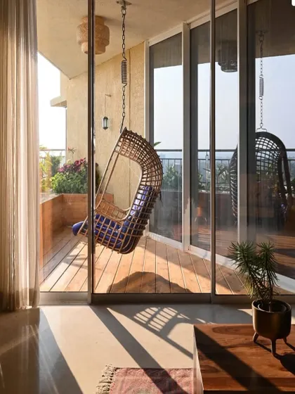 A sun-drenched balcony with a comfortable swing chair, creating a perfect spot to relax and enjoy the view.