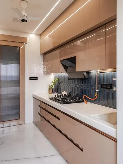 This angle shows the clean lines of the handleless drawers and the striking contrast between the glossy cappuccino cabinets and the dark blue backsplash. The integrated black chimney hood blends perfectly with the modern aesthetic.