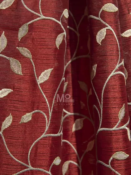 A rich red curtain fabric with embroidered golden leaves. This luxurious textile is curated to offer unmatched quality and sophistication for a bold statement.