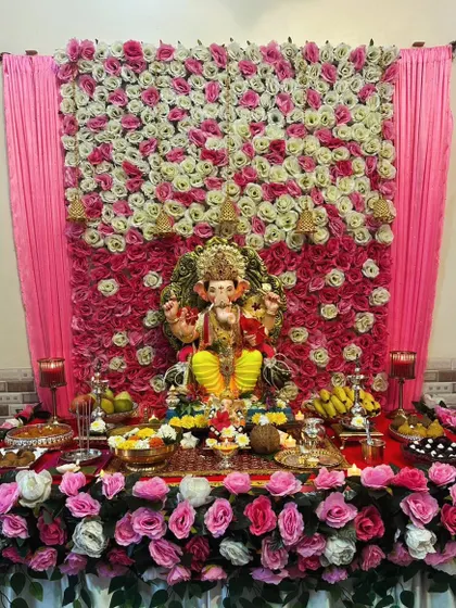 A beautiful wall of pink and white roses provides a classic and elegant backdrop for this Ganpati celebration. The decor extends to the base, creating a complete and cohesive floral look.