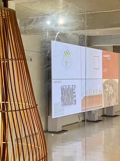 A closer view of the exhibition space, showing the interplay between the bespoke bamboo lighting, digital displays, and the overall architectural environment.