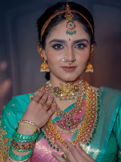 A close-up portrait that highlights the flawless skin and the intricate details of the temple jewellery. The makeup is designed to complement, not compete with, the accessories.