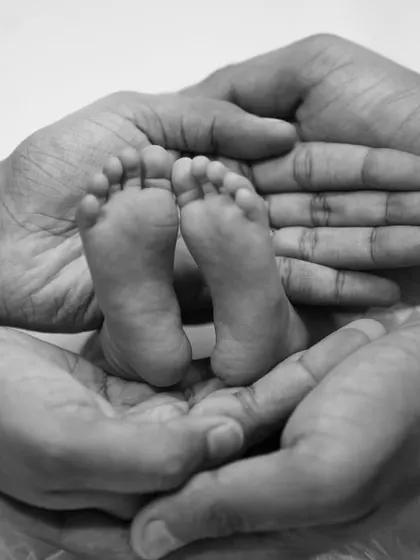 The tiniest feet make the biggest footprints in our hearts. This classic black and white shot of a newborn's feet held in their parents' hands is a timeless keepsake.