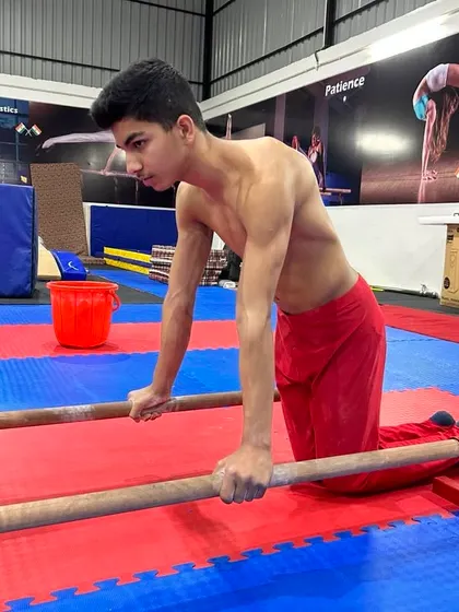 A young gymnast takes a moment during parallel bar training. Even rest is part of a structured workout.