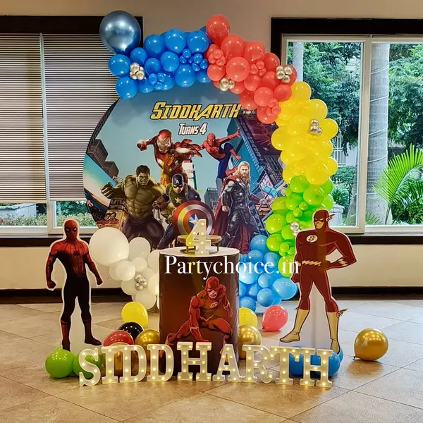 A fourth birthday reading Siddharth Turns 4: a round Avengers print in a blue, red, yellow and green garland, life-size Spider-Man and Flash cutouts, a printed plinth with a 4 and the name in lit letters