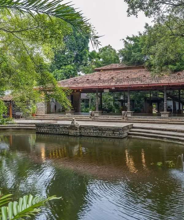This is the first view that greets you, our Pond Pavilion beside the serene kalyani. The calm water and ancient trees create a sense of peace, a perfect welcome to the property.