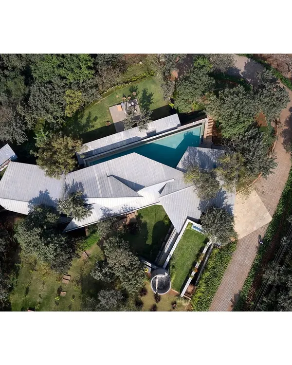 This is the Lateral Verandah House, a structure designed to converse with its landscape. The form is a direct response to the topography, with a roof that mirrors the stepped foundation, weaving around existing trees to create a home that feels born of the hill itself.