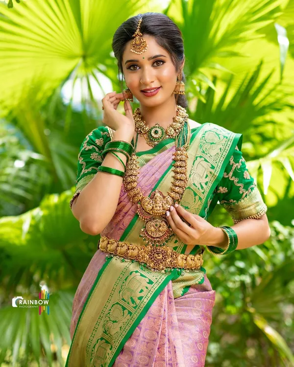 A beautiful bridal look featuring a classic Kanjivaram saree. The vibrant green and pink are set against a natural green background, making the temple jewellery and the fabric's gold zari work stand out.