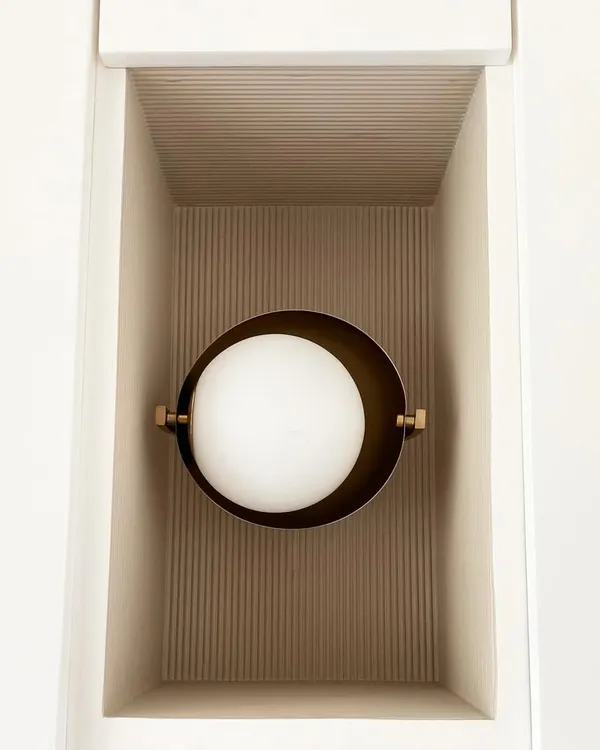 A simple niche transformed into a design feature. The fluted texture inside the niche catches the light beautifully, highlighting the modern, globe-shaped brass sconce.