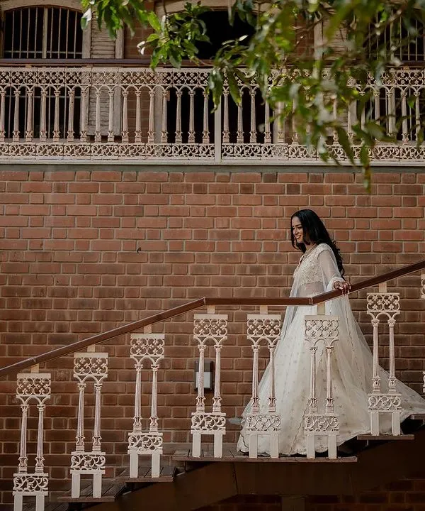 A beautiful bridal portrait of the bride descending a staircase. The architectural details and her elegant Tarun Tahiliani outfit create a timeless and graceful image.
