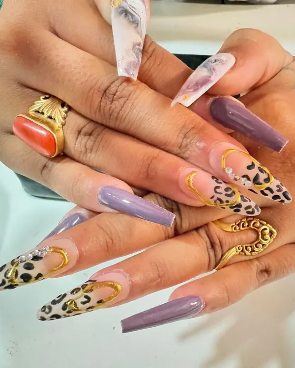 Go bold with these dramatic long nails. This set features a fierce combination of solid purple, marble, and a classic cheetah print with 3D gold chain details.