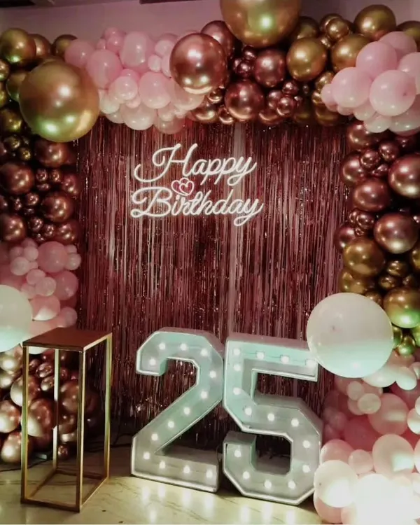 Celebrating a 25th birthday in style with a rose gold sequin backdrop, a matching balloon frame, and large '25' marquee numbers. It's a chic and modern setup perfect for photos.
