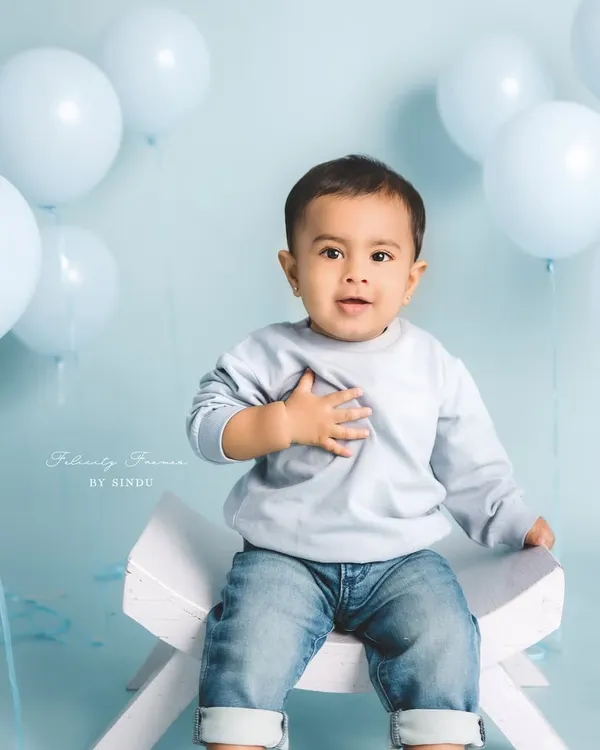 A classic sitter session portrait with a simple, clean background. This little boy's sweet expression and the soft blue tones create a timeless and heartwarming image.