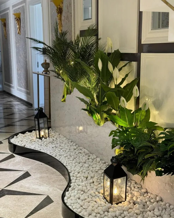 We transformed the often-overlooked space under a staircase into a serene focal point. This design uses a bed of white pebbles, elegant lanterns, and a curated selection of plants to create a hidden gem in the home.