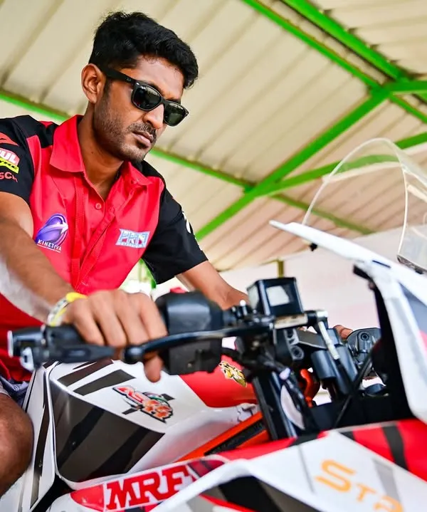 A coach on a race bike in the pits. The work behind the scenes is just as important as the action on the track.