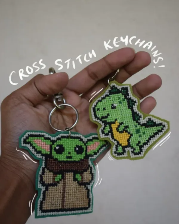 Here are two of my favorite cross-stitch keychains. I hand-stitch each one to look like pixel art, featuring a tiny Baby Yoda and a cute green dinosaur. They come with a sturdy clasp, perfect for adding some personality to your keys or bag.
