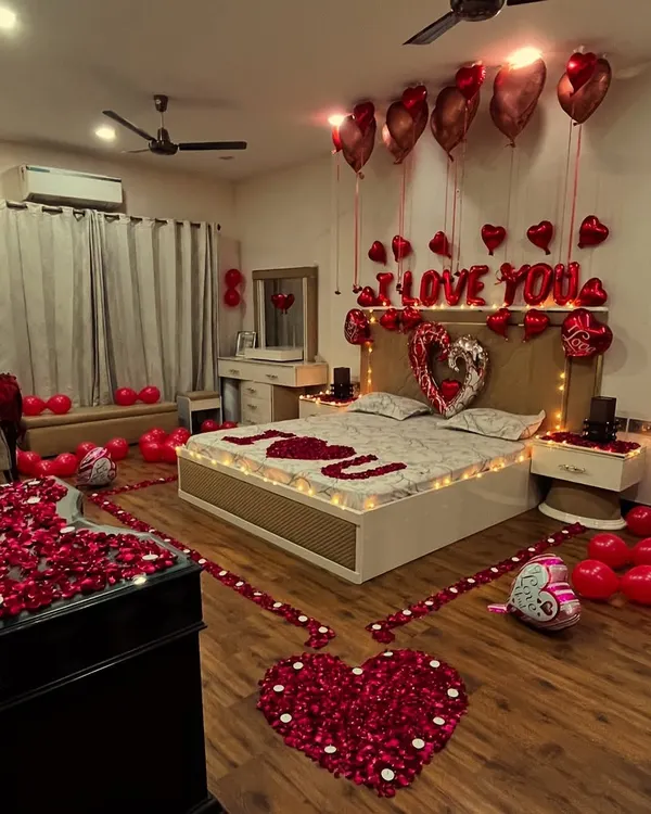 This is the full view of one of our most requested romantic room transformations. We use a combination of floor balloons, helium balloons, rose petal arrangements on the floor and bed, and custom foil letters to create a complete surprise experience.
