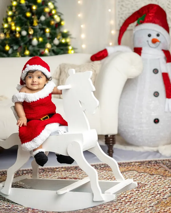 The magic of Christmas shines brightest through a child's eyes. This little Santa on her rocking horse, with a friendly snowman and twinkling tree, creates a perfect holiday card memory.