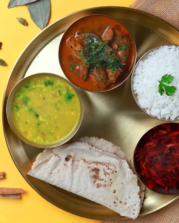 A complete, non-veg thali featuring our home-style chicken curry, dal, beetroot salad, steamed rice, and soft jowar rotis. A perfectly balanced meal to power your day.