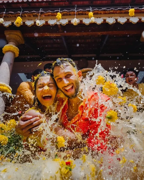 The peak of Haldi fun. This incredible action shot captures the couple's pure joy as they are drenched with water and flower petals, a perfect moment of celebration and togetherness.