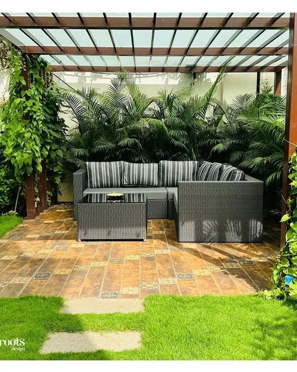 We designed this lush pergola lounge as the heart of the garden, a perfect sanctuary for morning chai or evening gatherings. The structure provides elegant shade over a patterned tile patio, surrounded by layered tropical plants to create a private, immersive outdoor living room.