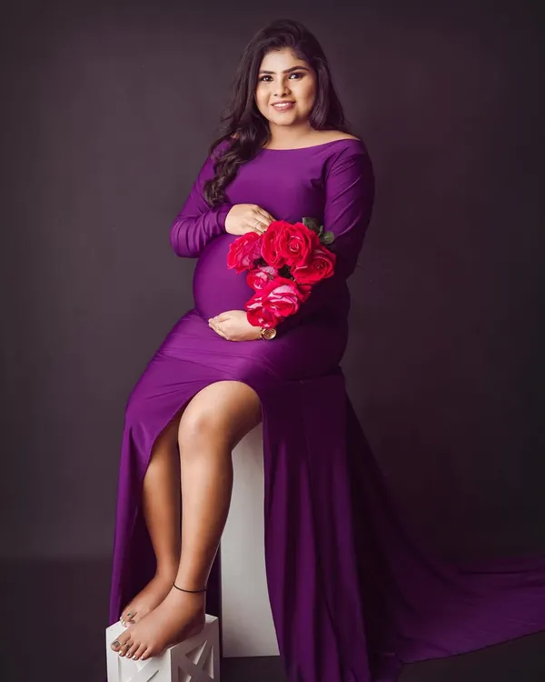 A bold and beautiful solo maternity portrait. The rich purple gown with its thigh-high slit and the pop of red roses create a truly glamorous and confident look.