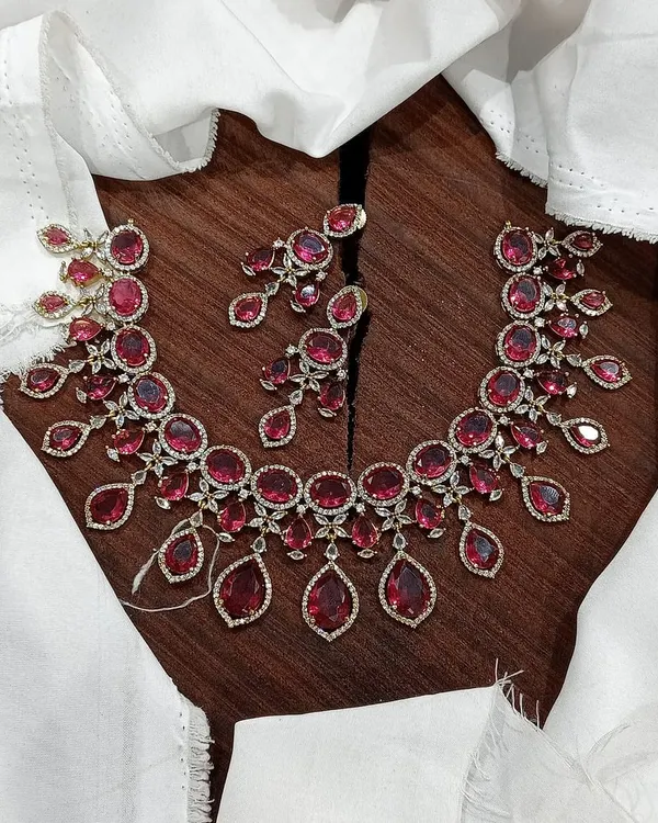 A stunning AD necklace set laid out to show its full design. This piece is available in multiple vibrant colors like ruby red, emerald green, pastel blue, and sapphire blue, featuring teardrop-shaped stones.